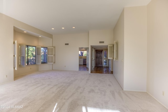 carpeted spare room featuring a towering ceiling