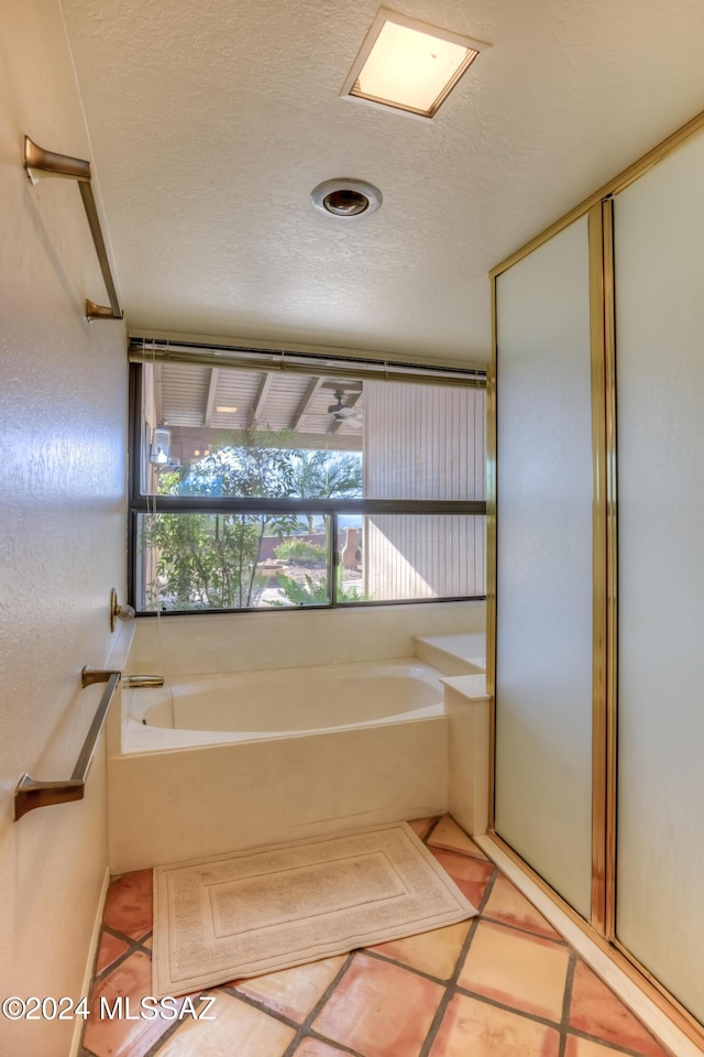 bathroom with a textured ceiling, tile patterned floors, and a tub