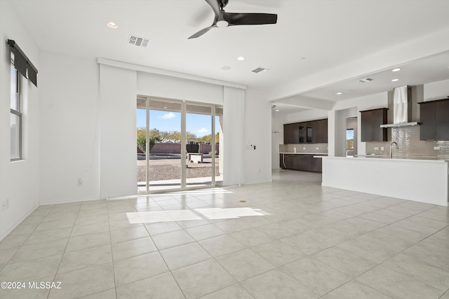 unfurnished living room featuring ceiling fan, sink, and light tile patterned floors