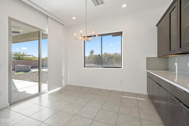 unfurnished dining area featuring light tile patterned flooring and a chandelier