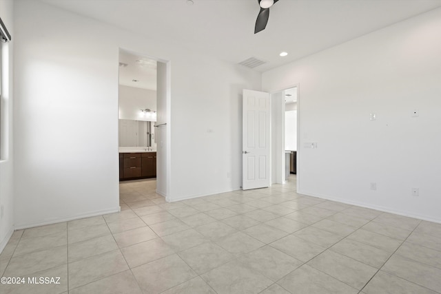 unfurnished bedroom with ensuite bath, ceiling fan, and light tile patterned flooring