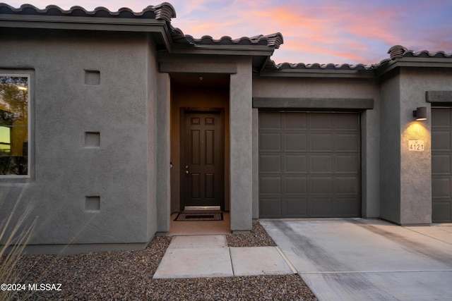 exterior entry at dusk featuring a garage