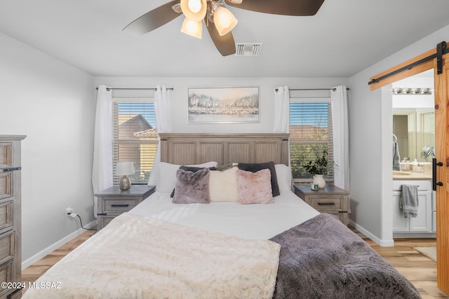 bedroom featuring multiple windows, a barn door, and light hardwood / wood-style flooring