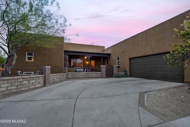 pueblo-style home featuring a porch and a garage