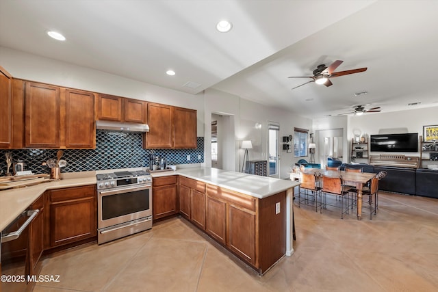 kitchen featuring ceiling fan, stainless steel appliances, kitchen peninsula, decorative backsplash, and light tile patterned floors