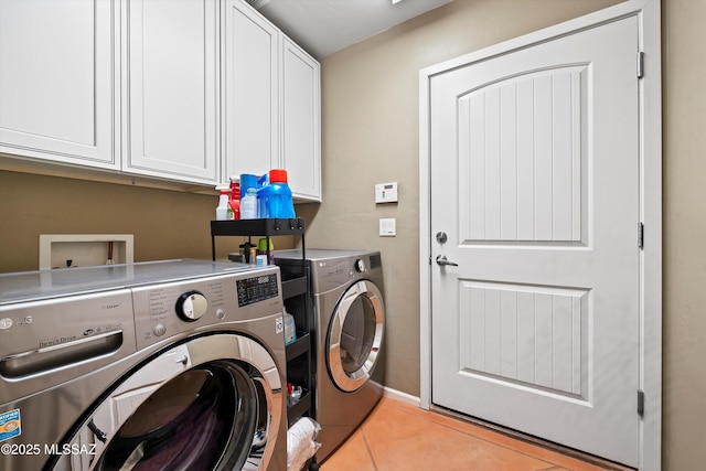 laundry room featuring washer and clothes dryer, cabinets, and light tile patterned floors