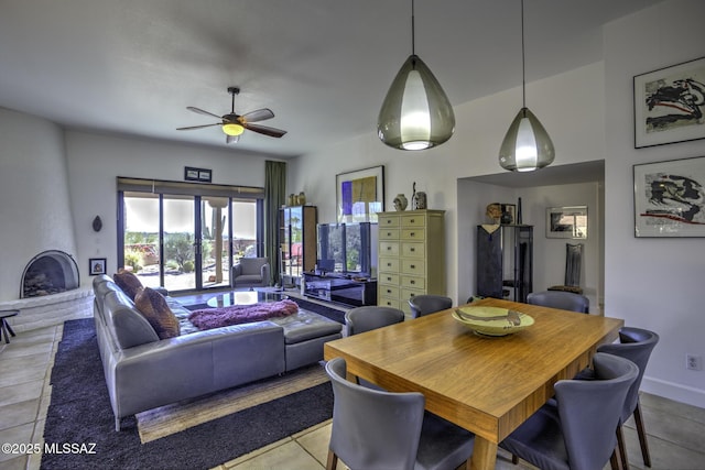 tiled dining room featuring a fireplace and ceiling fan