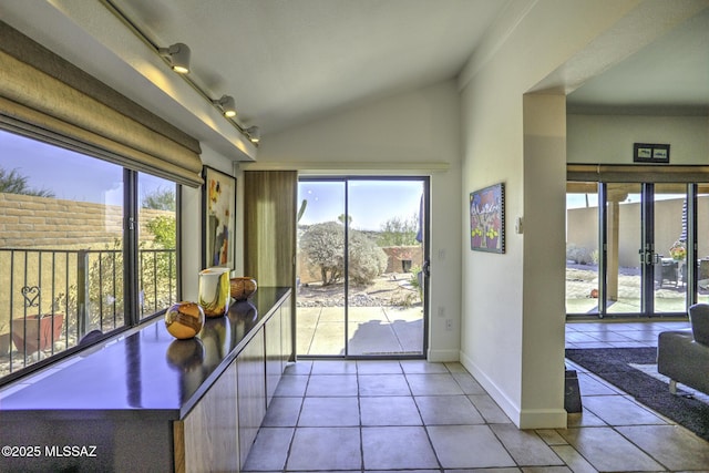 interior space featuring track lighting, lofted ceiling, and light tile patterned floors