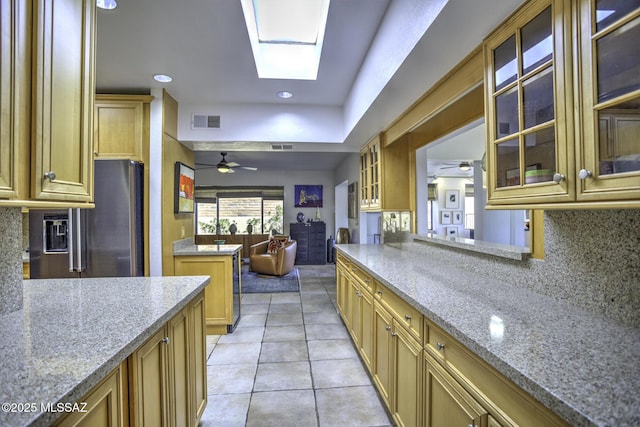 kitchen featuring a skylight, light tile patterned floors, light stone countertops, and backsplash