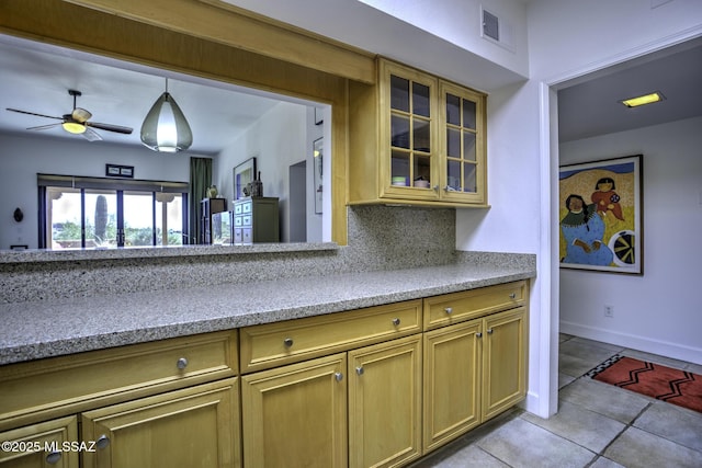 kitchen with pendant lighting, light tile patterned floors, ceiling fan, backsplash, and light stone countertops