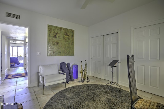 living area with light tile patterned floors and ceiling fan