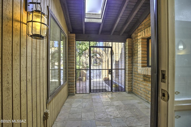 unfurnished sunroom with vaulted ceiling with skylight