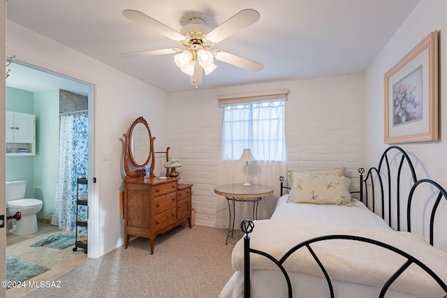 bedroom with ensuite bath, ceiling fan, and brick wall