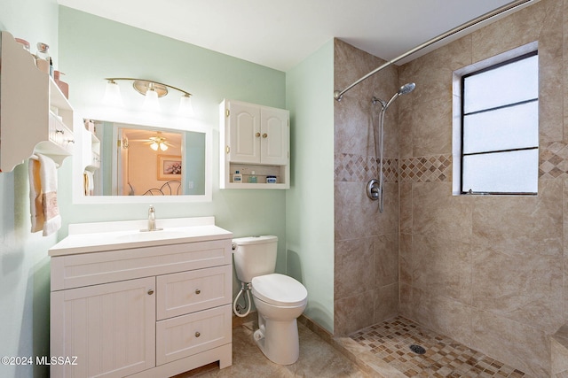 bathroom featuring vanity, ceiling fan, toilet, and a tile shower