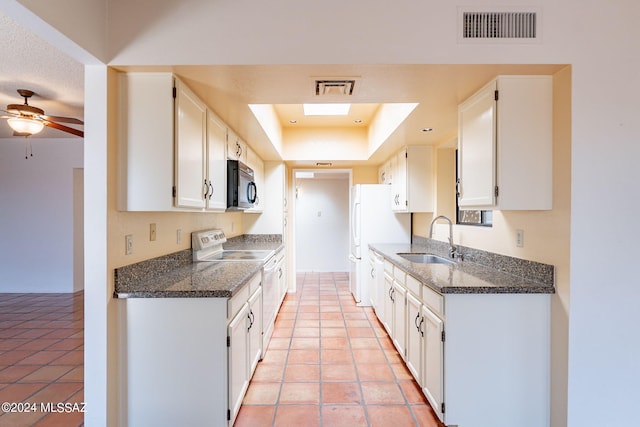 kitchen featuring a tray ceiling, white cabinetry, sink, and white appliances