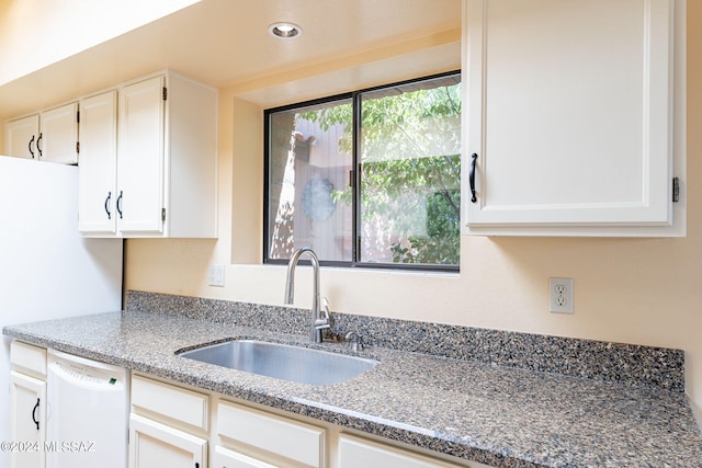 kitchen with light stone counters, dishwasher, white cabinets, and sink