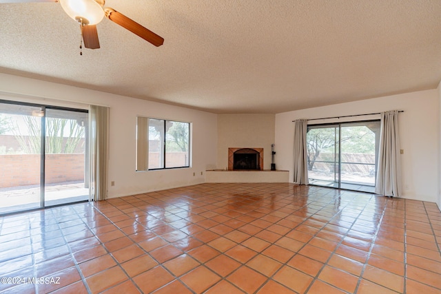 unfurnished living room featuring a healthy amount of sunlight, light tile patterned floors, and a textured ceiling