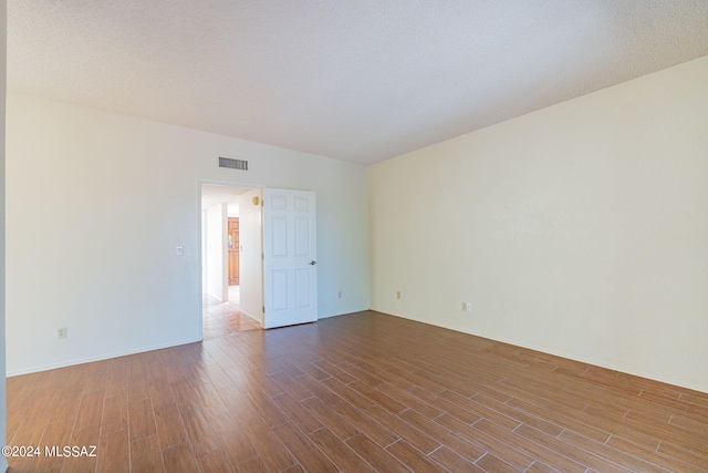 unfurnished room with a textured ceiling and hardwood / wood-style flooring