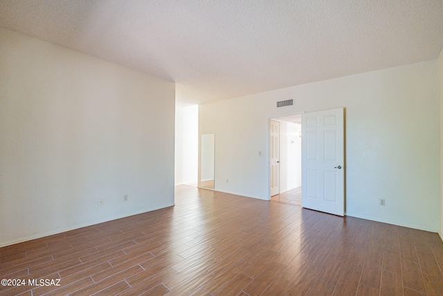 spare room with dark hardwood / wood-style floors and a textured ceiling