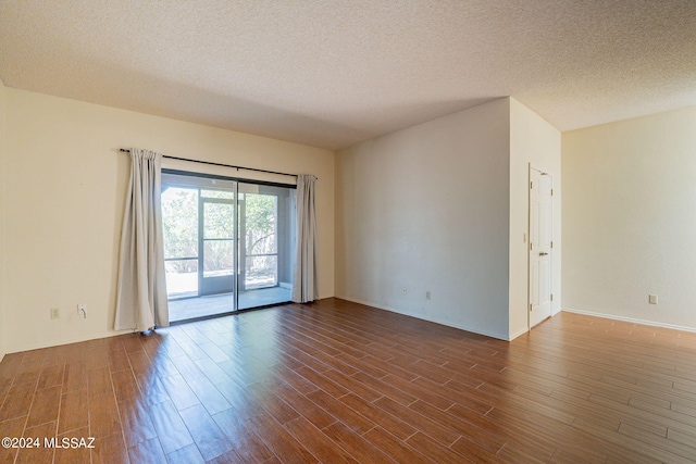 spare room featuring dark hardwood / wood-style flooring and a textured ceiling