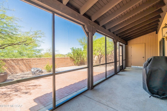 unfurnished sunroom with lofted ceiling with beams and a wealth of natural light