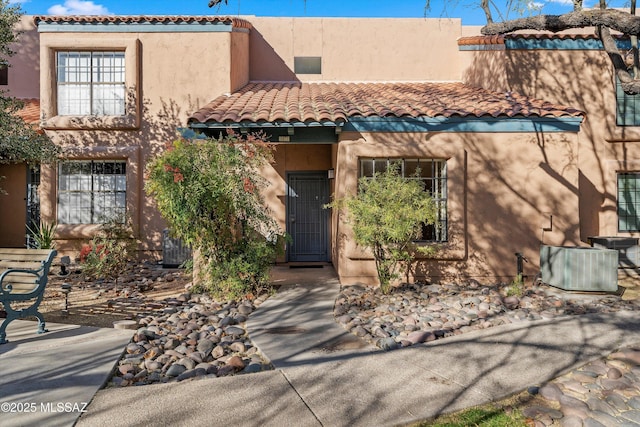 view of front of home featuring a tiled roof, central AC, and stucco siding