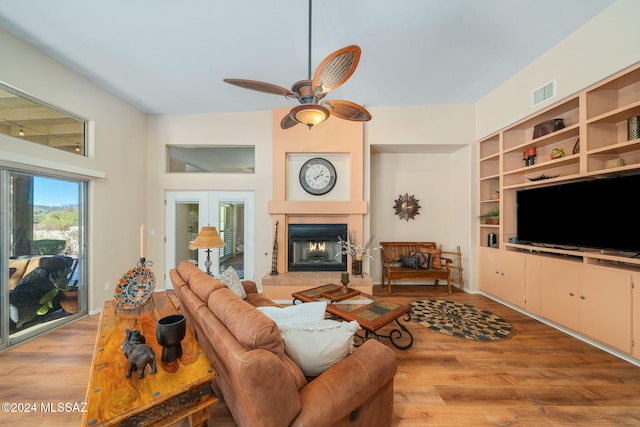 living room featuring ceiling fan, light hardwood / wood-style floors, and built in shelves