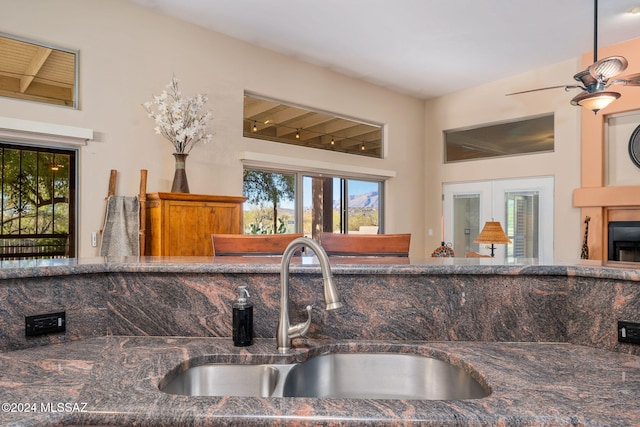 kitchen featuring ceiling fan, sink, dark stone counters, and french doors