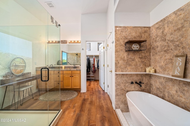 bathroom with vanity, a tub to relax in, tile walls, and hardwood / wood-style flooring