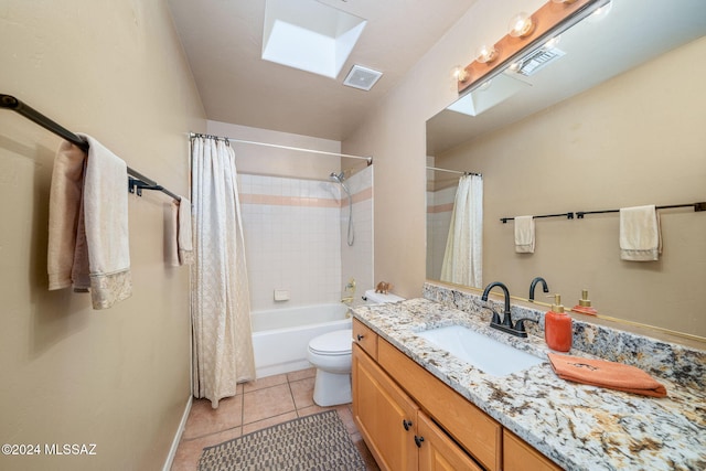 full bathroom with vanity, tile patterned floors, a skylight, toilet, and shower / bath combo with shower curtain