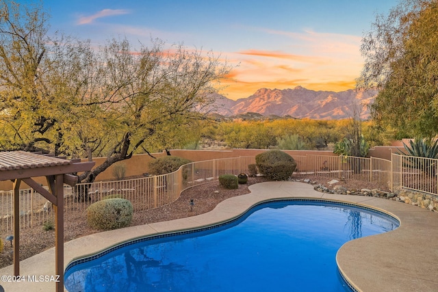 pool at dusk featuring a mountain view