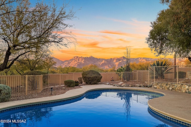 pool at dusk featuring a mountain view