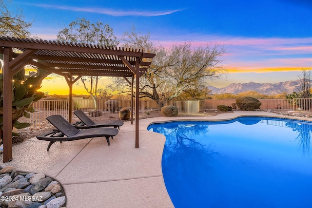 pool at dusk with a pergola, a patio area, and a mountain view