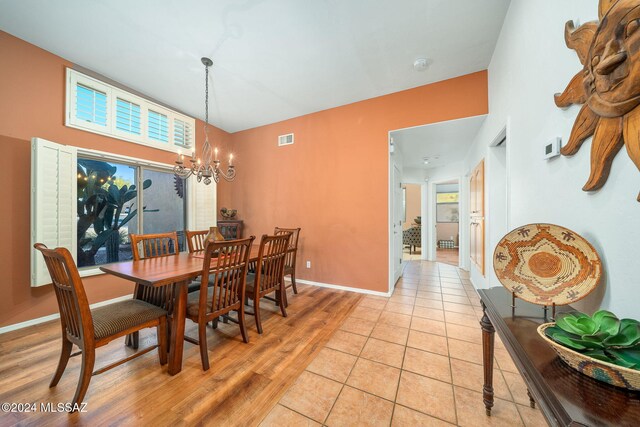 dining area with light wood-type flooring and an inviting chandelier