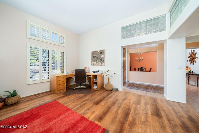 office area featuring hardwood / wood-style floors, a high ceiling, and an inviting chandelier