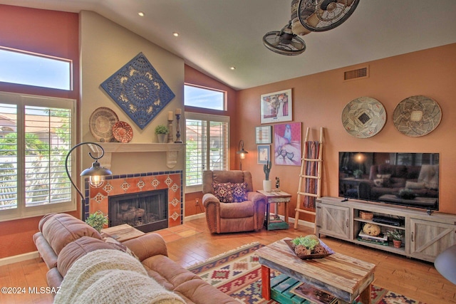 living room with a fireplace, wood-type flooring, high vaulted ceiling, and a healthy amount of sunlight