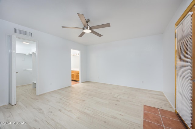 unfurnished bedroom with ceiling fan, a spacious closet, connected bathroom, and light hardwood / wood-style flooring