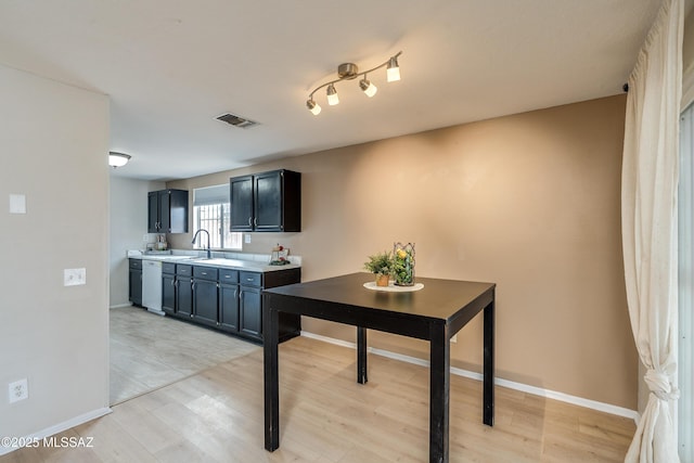 kitchen with sink, white dishwasher, and light hardwood / wood-style floors