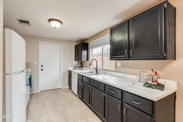 kitchen with white appliances, light stone countertops, and sink