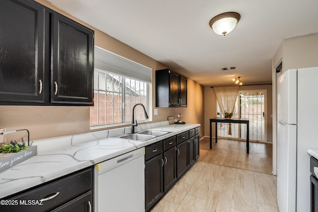 kitchen with sink, light stone counters, and white appliances