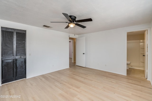 unfurnished bedroom with ceiling fan, ensuite bathroom, a closet, and light wood-type flooring