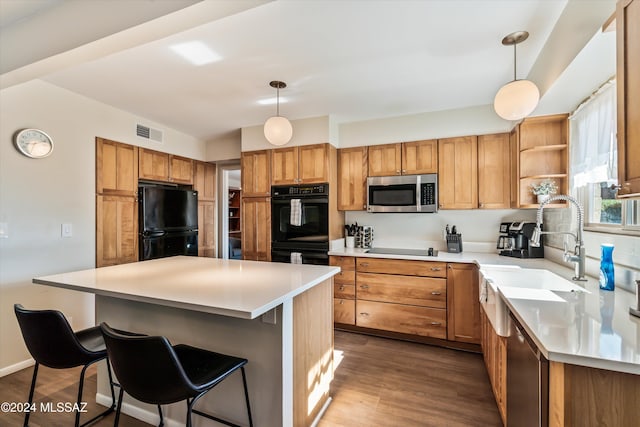 kitchen with visible vents, black appliances, a breakfast bar, and wood finished floors