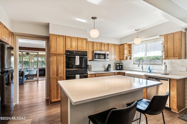 kitchen featuring tasteful backsplash, dark wood-type flooring, black appliances, decorative light fixtures, and a kitchen island