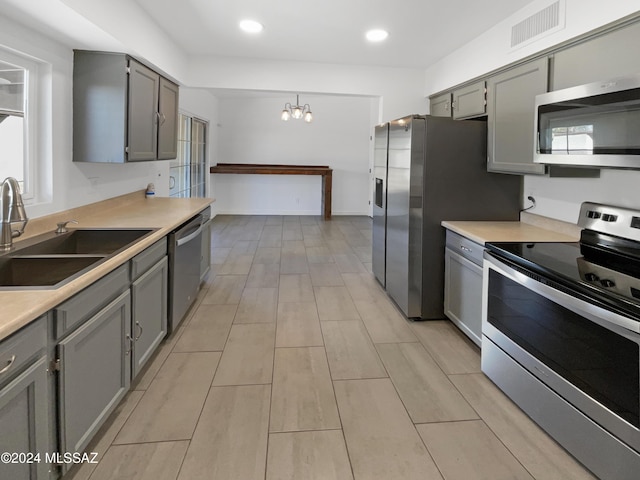 kitchen featuring an inviting chandelier, sink, gray cabinets, decorative light fixtures, and stainless steel appliances