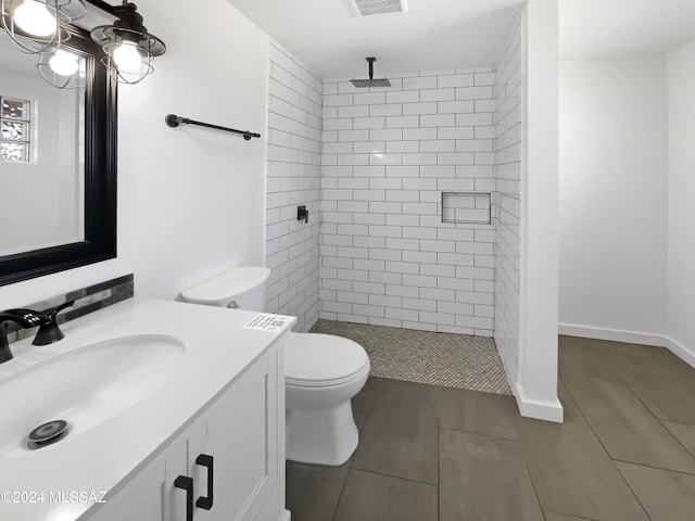 bathroom featuring tile patterned floors, vanity, toilet, and a tile shower