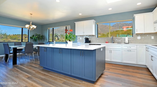 kitchen with white cabinetry, a center island, light hardwood / wood-style flooring, and decorative light fixtures