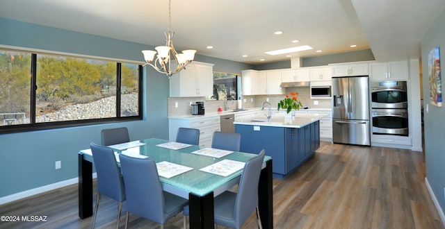 kitchen with pendant lighting, sink, appliances with stainless steel finishes, white cabinets, and decorative backsplash