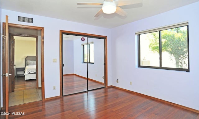 unfurnished bedroom with dark hardwood / wood-style flooring, a closet, and ceiling fan