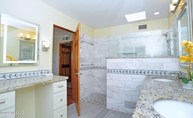 bathroom featuring vanity, a skylight, and a tile shower