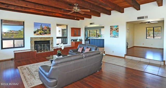 living room with beam ceiling, hardwood / wood-style flooring, a premium fireplace, and ceiling fan